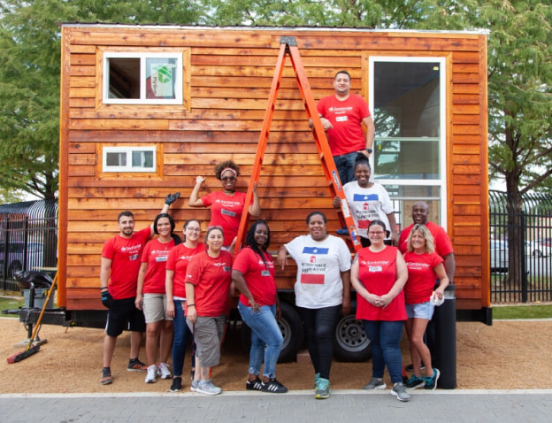 Employees in red Santander t-shirts posed in front of a home they are building