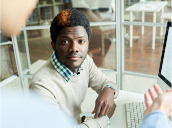 Two men speaking in front of a computer