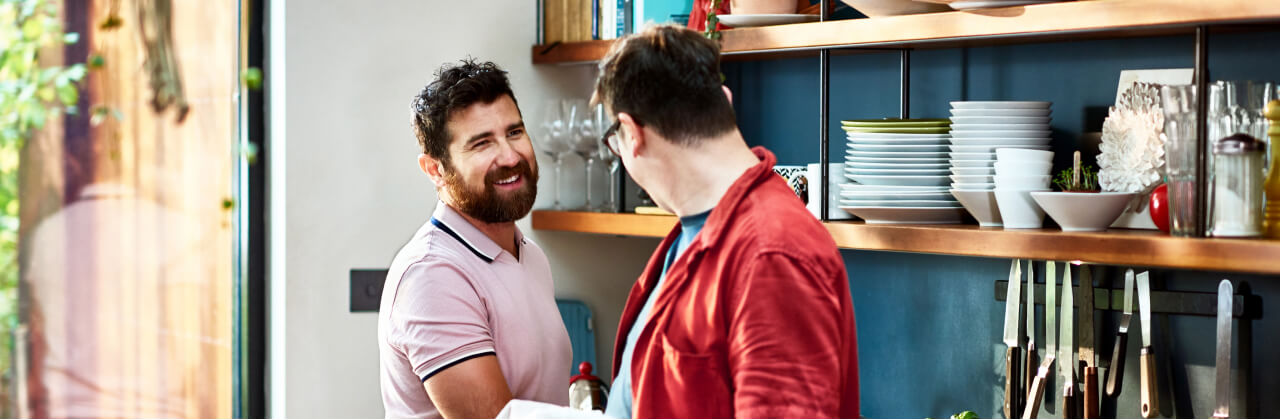 two men at the sink washing dishes and talking