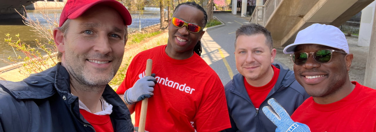 Employees in red Santander t-shirts posing while cleaning up landscaping