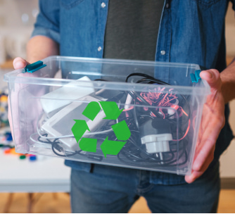 A man holding a clear recycling box of various electronic parts.