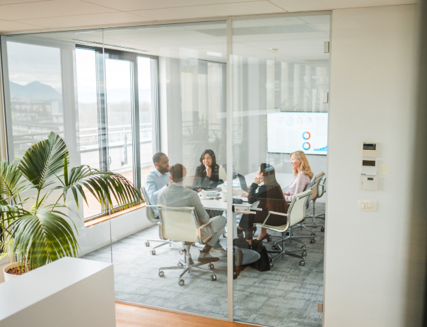 A group of five people sitting at a table in a meeting room talking.