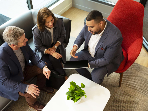 Man presenting material to a woman and man on a tablet.