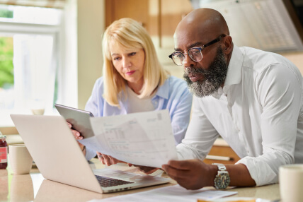 woman and a man looking at paperwork in front of a laptop
