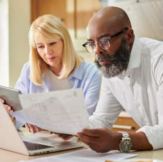woman and a man looking at paperwork in front of a laptop