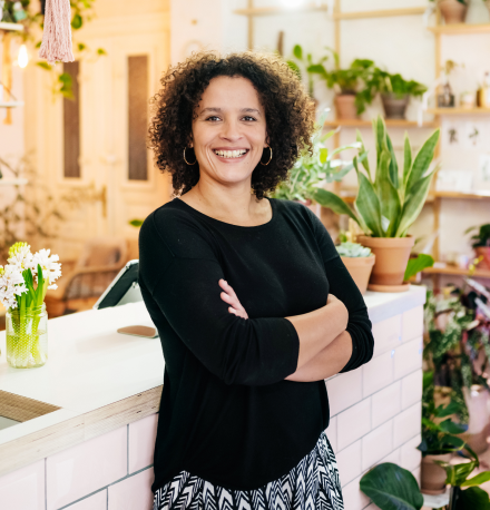 A woman leaning on the front counter in a plant shop.