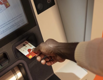 A person inserting a debit card into an ATM slot.