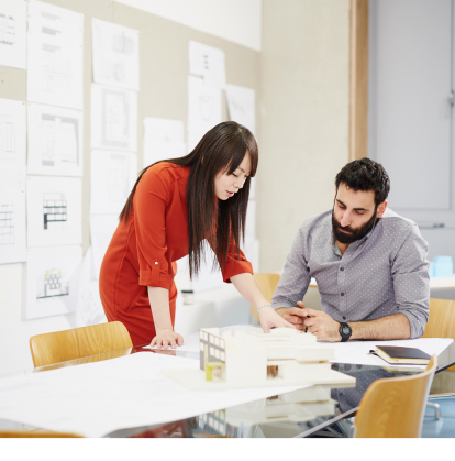 A man and woman in a business office, examining papers.