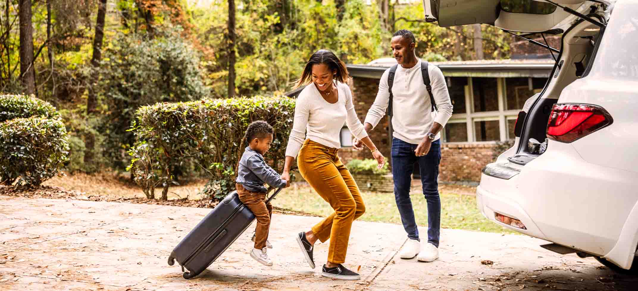 A family walking toward a car going on vacation