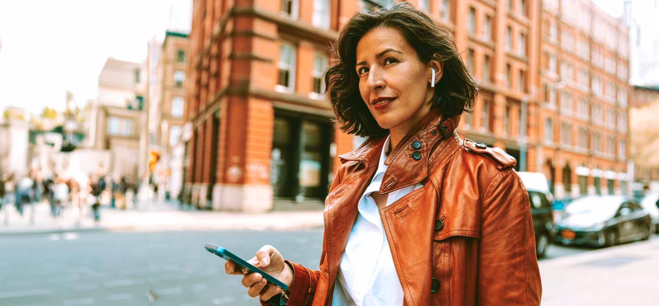 Woman walking in city street with phone in hand.