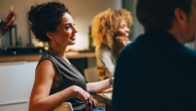 Woman at elegant dinner leaning back in chair while having a conversation
