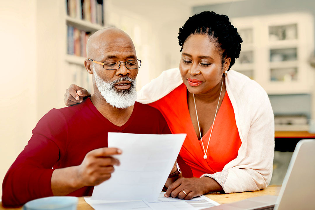A couple in front of a computer looking at a document