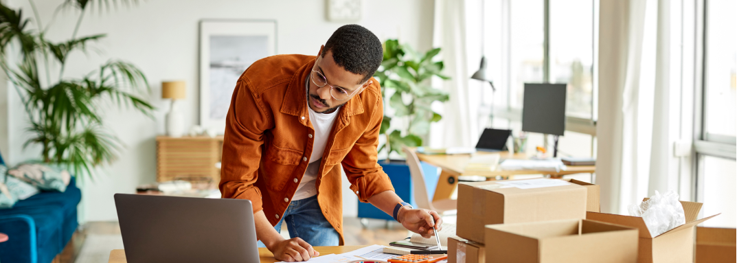 Man looking at laptop and packaging boxes