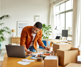 Man looking at laptop and packaging boxes