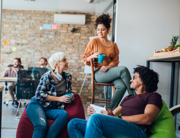 A group of 3 friends hanging out in a lounge area and having coffee together