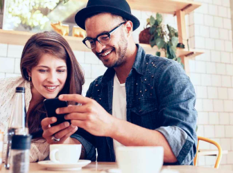 Man and woman looking at mobile device in coffee shop