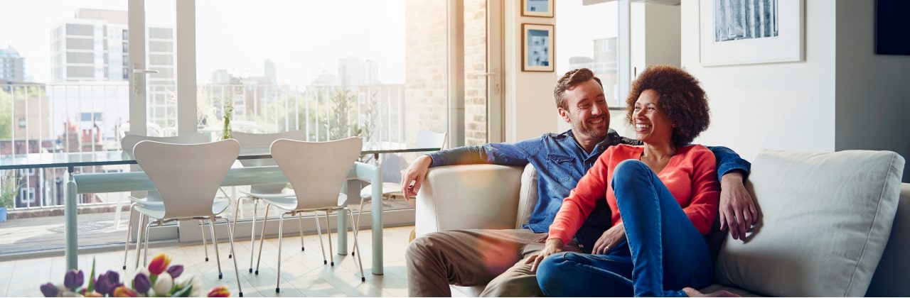 A male and female couple are relaxing on a living room couch