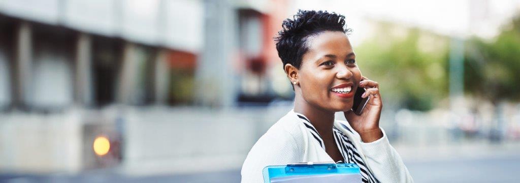 A woman smiling and looking into the distance while talking on the phone