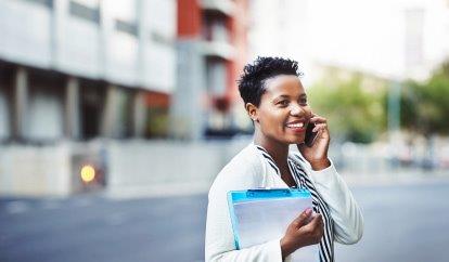 A woman smiling and looking into the distance while talking on the phone