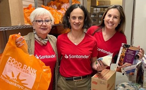 Employees in red Santander t-shirts posed in front of a home they are building
