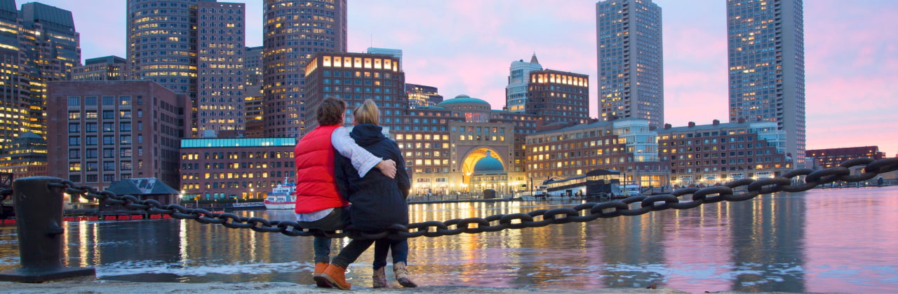 Illustration of a man and woman looking across a river at a city scape during dusk