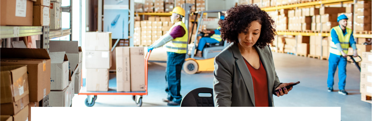 Woman in blazer in warehouse holding a cell phone