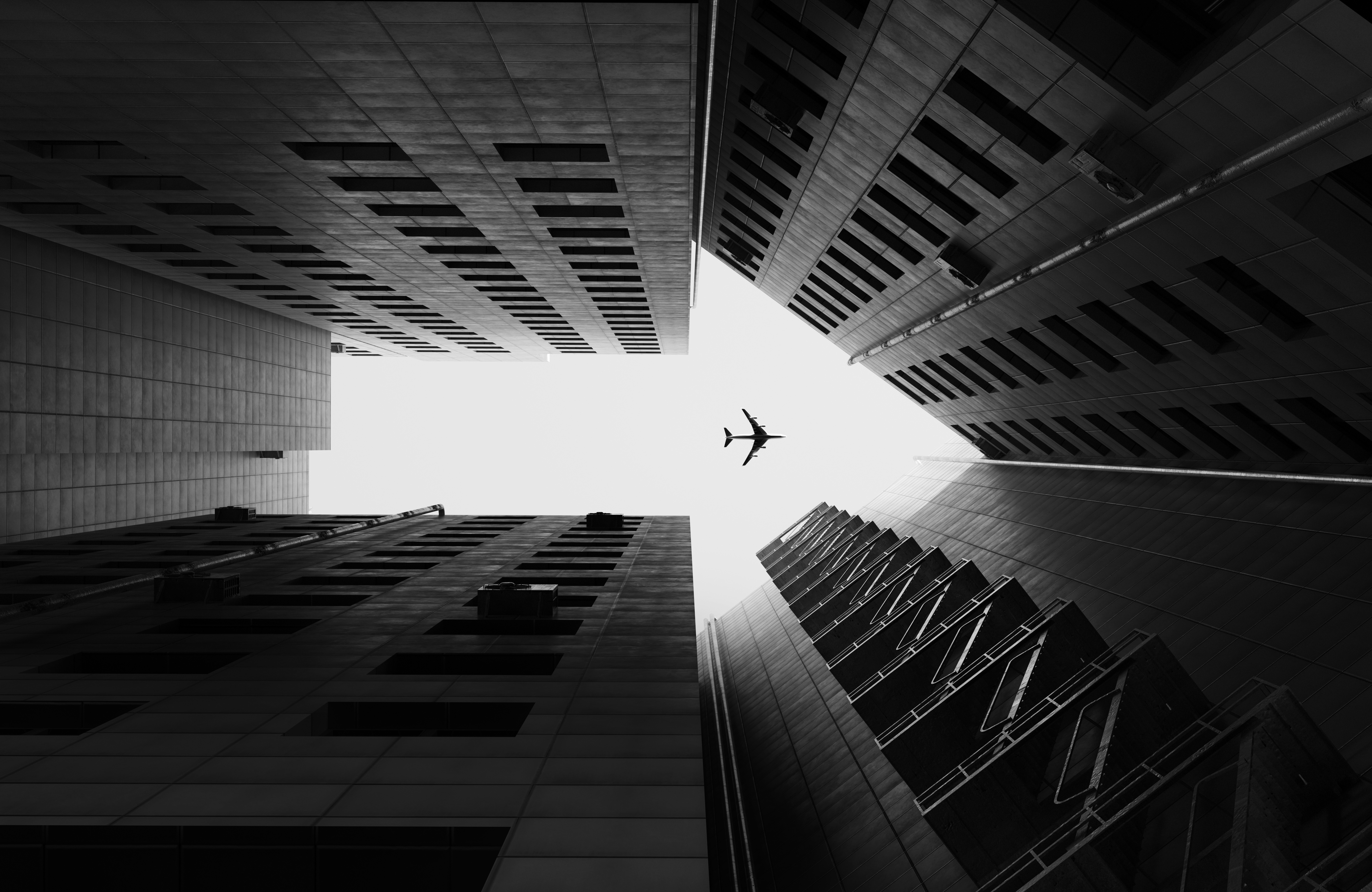 Airplane flying overhead above tall skyscrapers