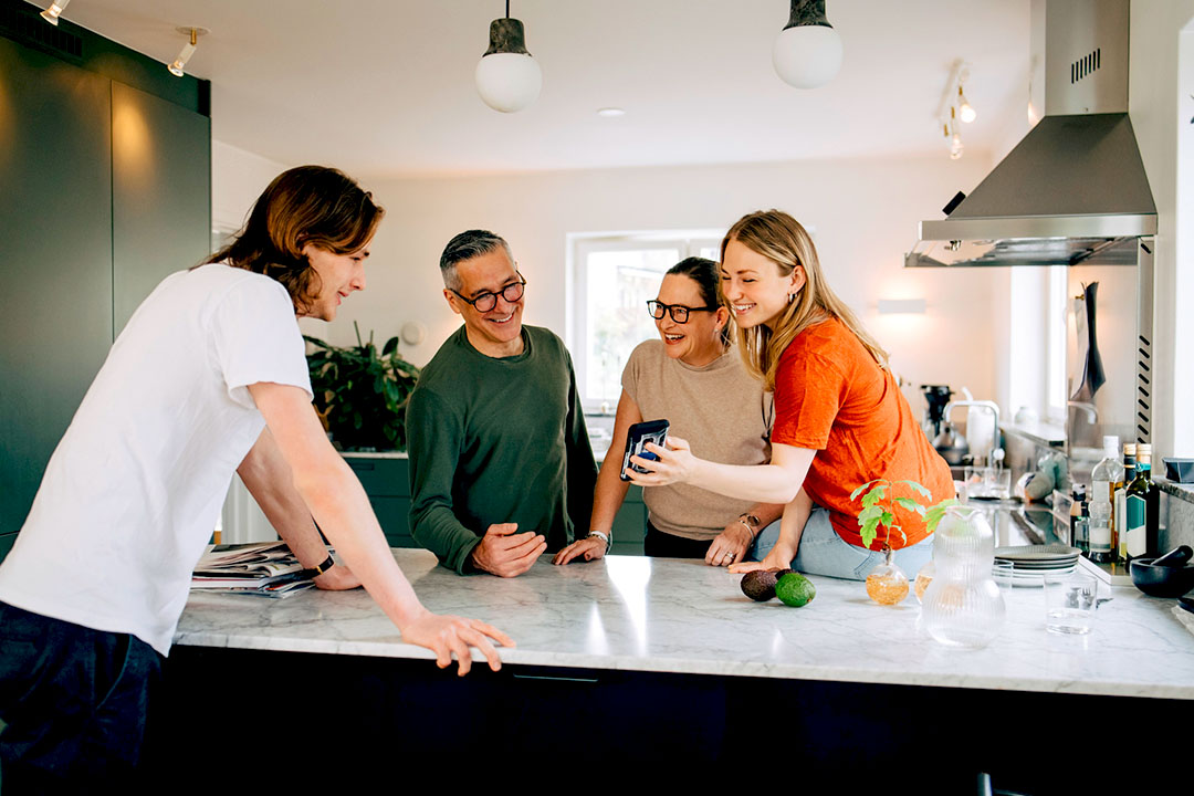 People viewing phone while leaning on kitchen counter