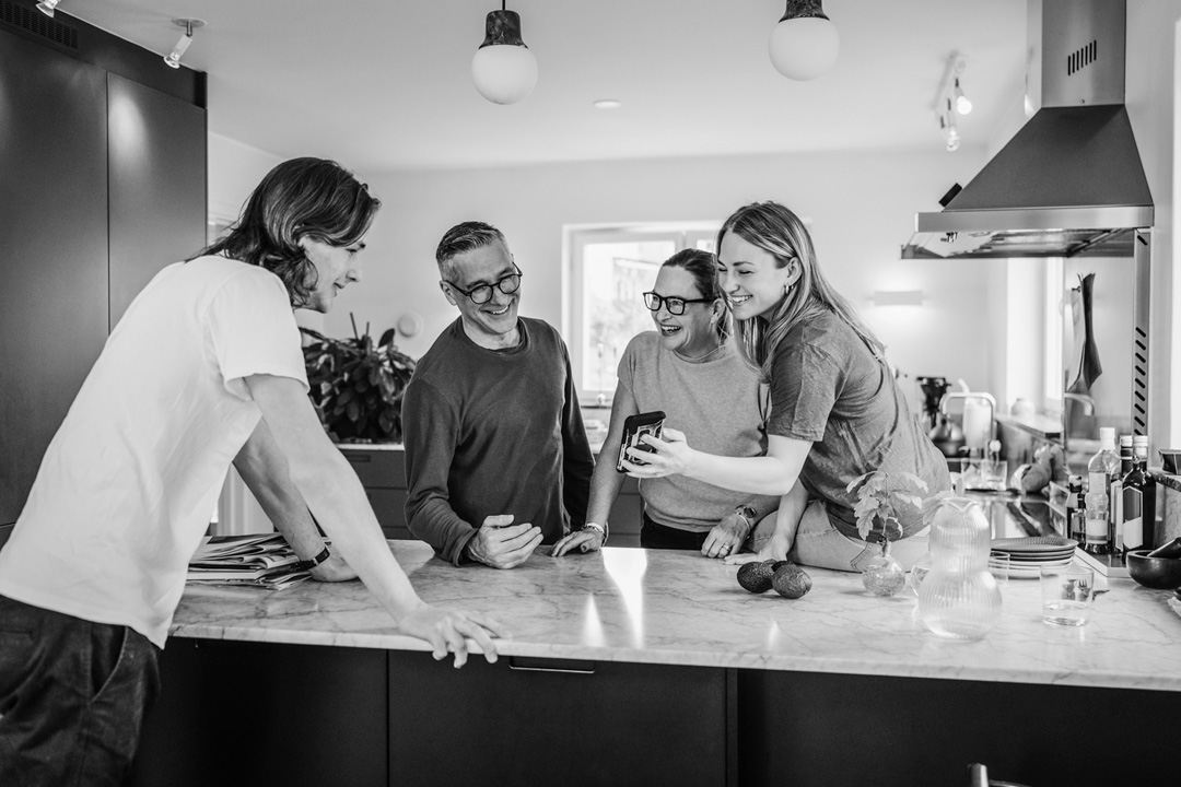 People viewing phone while leaning on kitchen counter